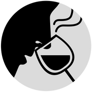 The silhouette of a person sniffing a wine glass.